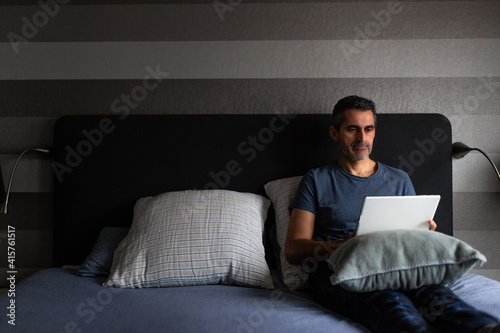 Man working in bed with a digital tablet