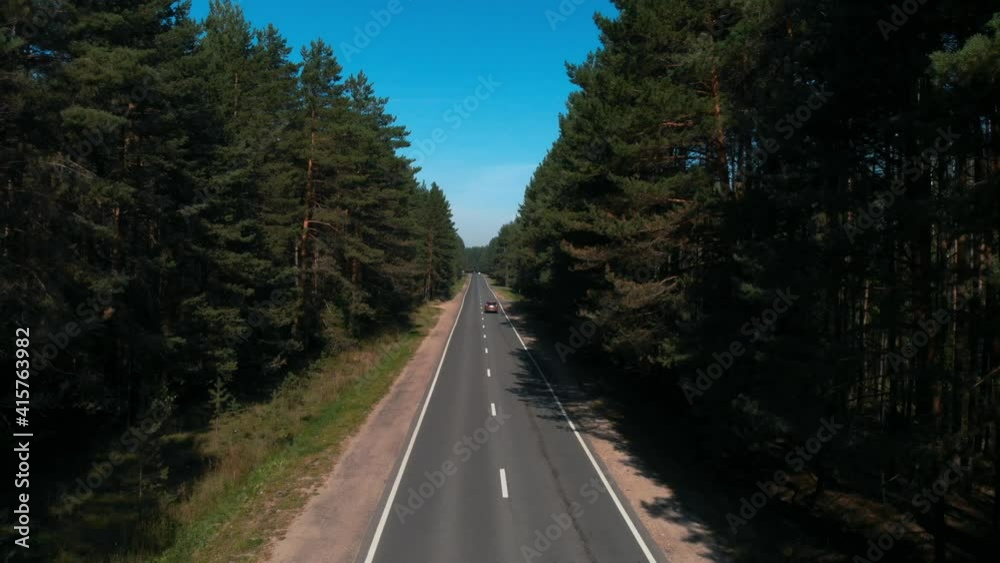 Moving aerial view from drone on highway going through pine wood. Overhead scene with beautiful landscape of tall green forest with road in a middle. Concept of transportation, nature, travel. Moving aerial view from drone on highway going through pine wood. Overhead scene with beautiful landscape of tall green forest with road in a middle. Concept of transportation, nature, travel.