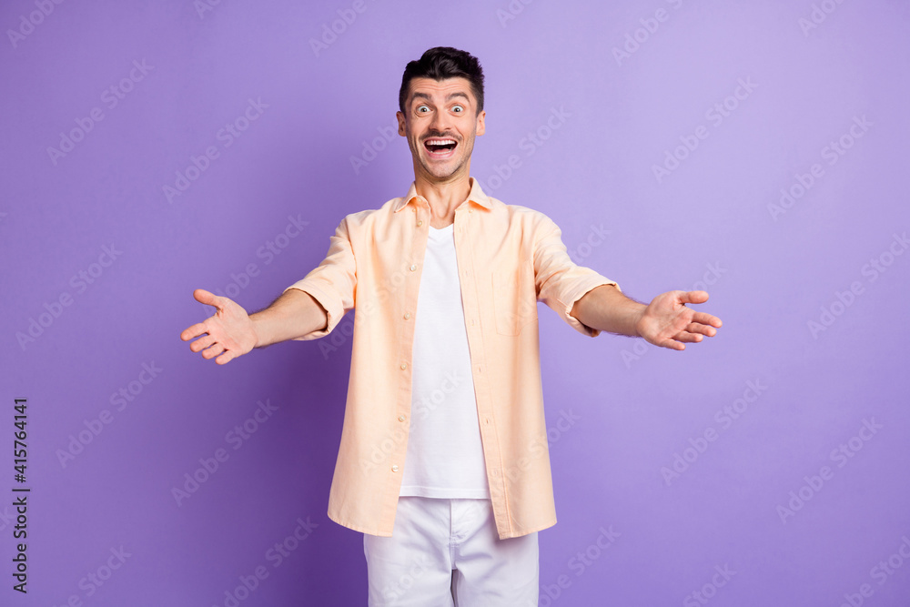 Photo of optimistic brunet guy hands want hug wear peach shirt pants isolated on lilac color background Photo of optimistic brunet guy hands want hug wear peach shirt pants isolated on lilac color background