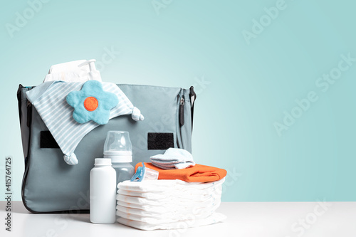 Bag packed for trip or journey or for walking with baby. Diapers, bottle and other necessary things for baby and mom. Diaper bag to maternity hospital. Copy space. Blue background. 