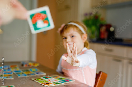 Adorable cute toddler girl playing picture card game. Happy healthy child training memory, thinking. Creative indoors leisure and education of kid during pandemic coronavirus covid quarantine disease