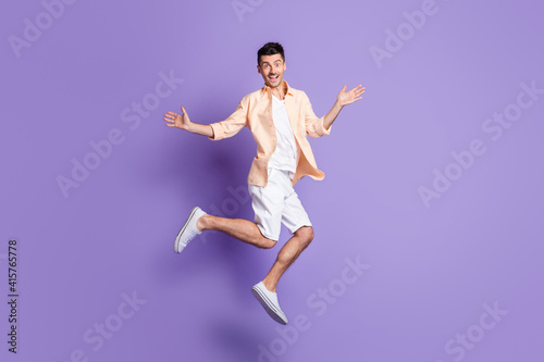 Fototapeta Naklejka Na Ścianę i Meble -  Full size profile photo of hooray brunet guy jump dance wear peach shirt shorts sneakers isolated on lilac background
