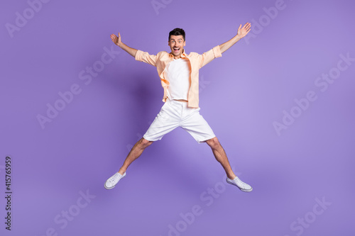 Full size photo of hooray brunet guy jump wear peach shirt shorts sneakers isolated on lilac background