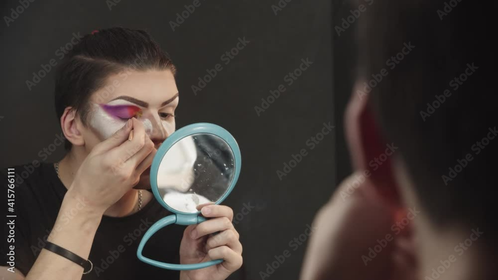 Drag artist - young man applying red eyeshadows on the inner corner Drag artist - young man applying red eyeshadows on the inner corner