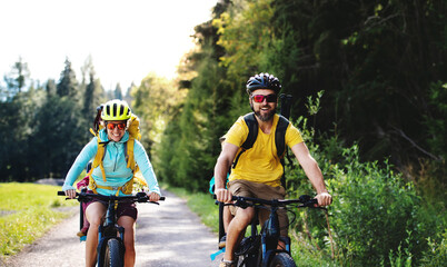 Family with small children cycling outdoors in summer nature.