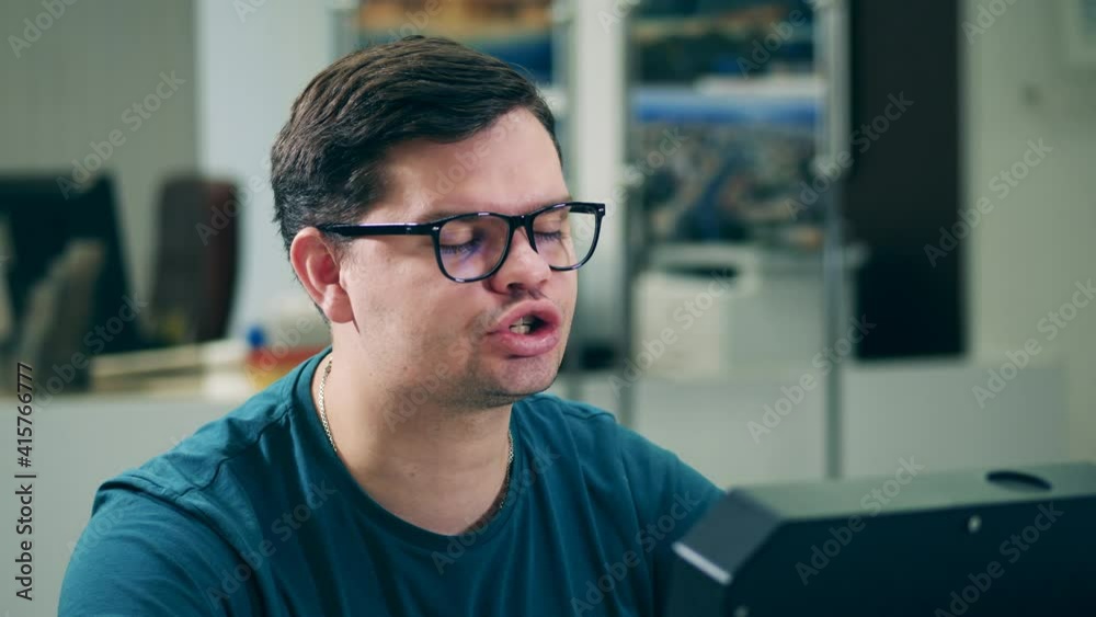 A man in glasses is talking to someone in the office A man in glasses is talking to someone in the office