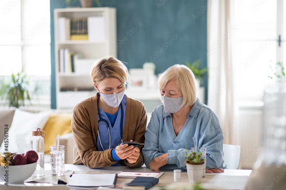 Caregiver or healthcare worker with senior woman patient, measuring blood glucose indoors. Caregiver or healthcare worker with senior woman patient, measuring blood glucose indoors.