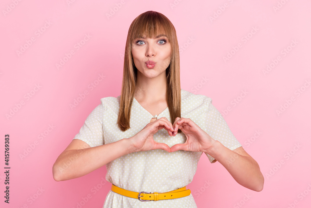 Portrait of attractive amorous girl showing heart symbol sending air kiss isolated over pink pastel color background Portrait of attractive amorous girl showing heart symbol sending air kiss isolated over pink pastel color background