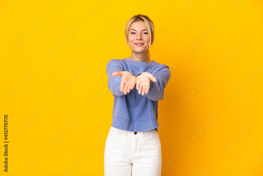 Young Russian woman isolated on yellow background holding copyspace imaginary on the palm to insert an ad Young Russian woman isolated on yellow background holding copyspace imaginary on the palm to insert an ad