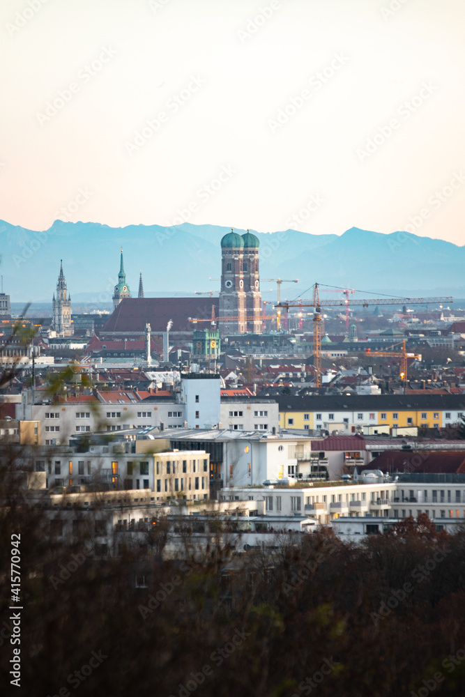 sunset over the city of München with the Alps in the background
