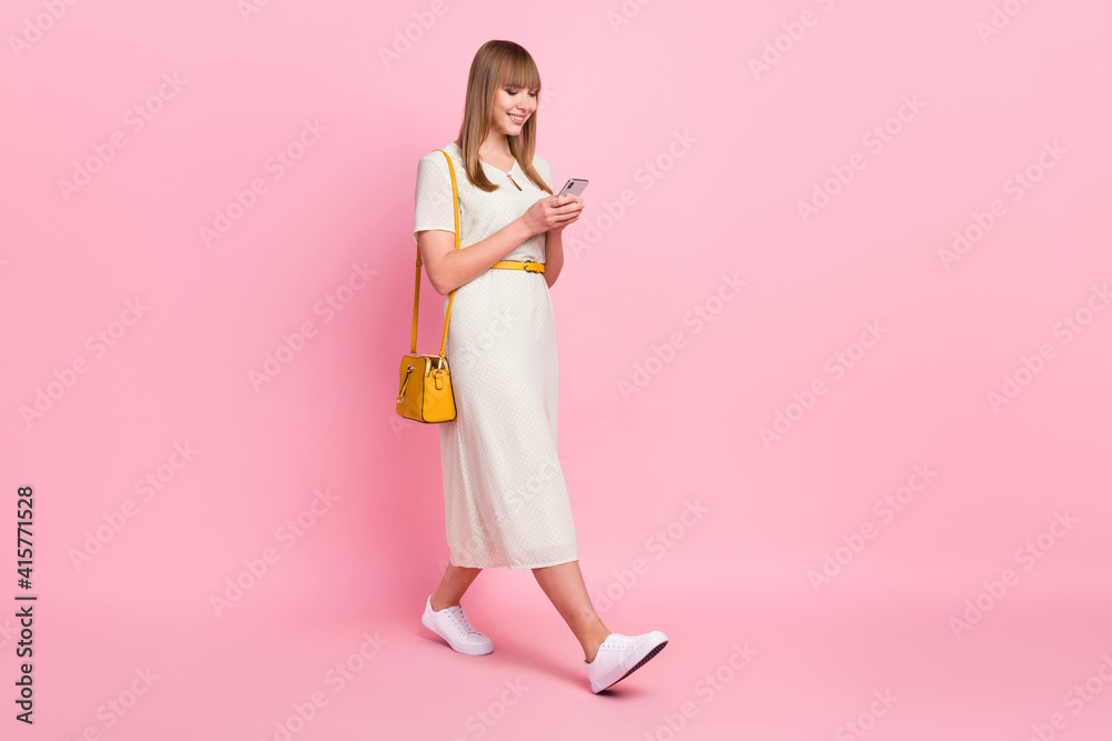 Full length body size profile side view of nice focused addicted cheerful girl going using device isolated over pink pastel color background Full length body size profile side view of nice focused addicted cheerful girl going using device isolated over pink pastel color background