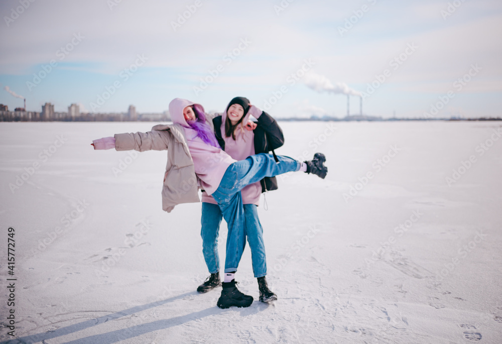two girlfriends have fun in the snow in winter