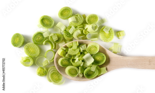 Chopped leek slices pile with wooden spoon isolated on white background, top view