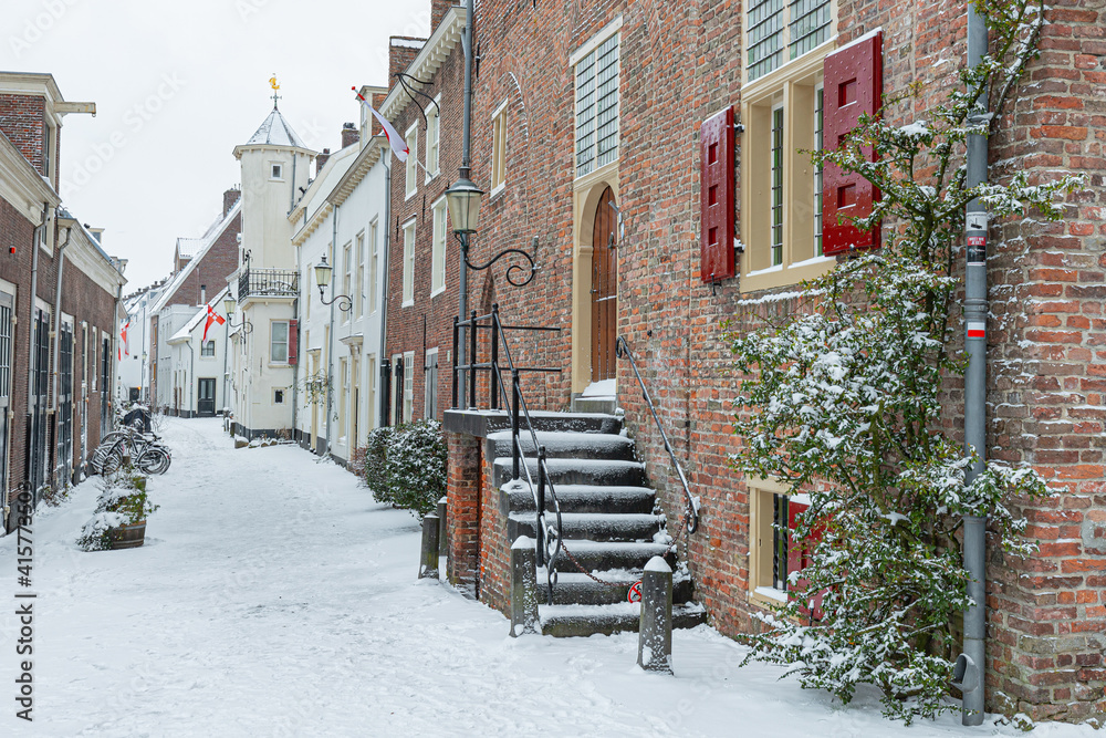 A wintry cityscape of the medieval city of Amersfoort in the center of the Netherlands. Buildings and streets are covered with snow.
