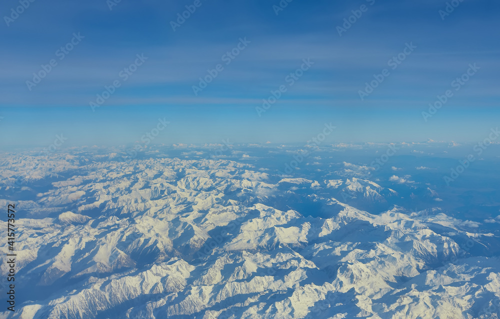 Aerial landscape of the Alps in Europe during winter season with fresh snow. View from the airplane window