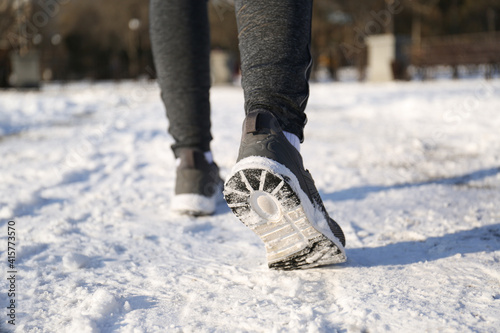 Woman running along park on winter day, closeup. Outdoors sports exercises