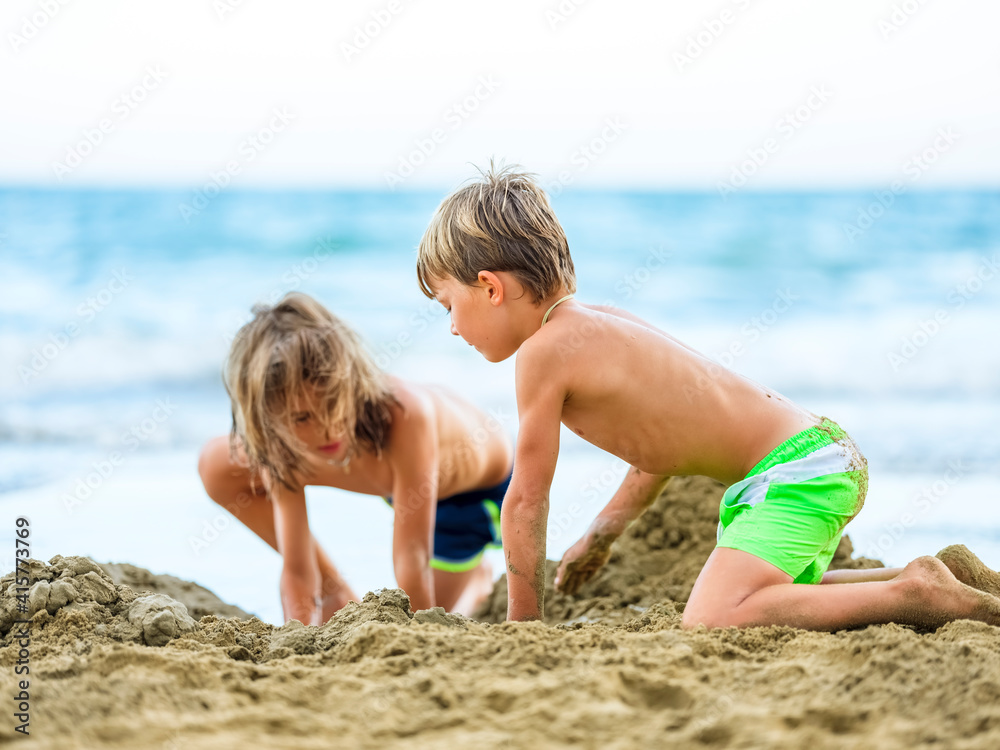 The child in a bathing suit plays on the sand at the beach on a sunny day.