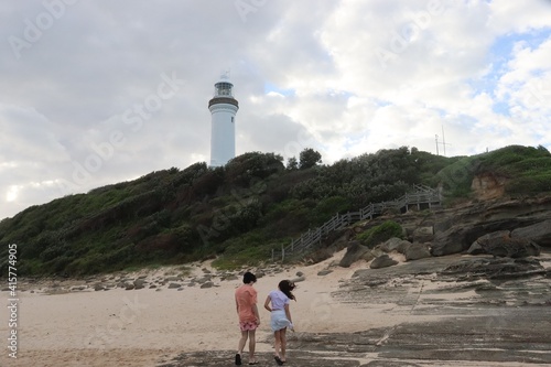 The sky is turning gray , wind is blowing in their direction. Two teenagers in a hurry to reach the lighthouse on top of the hill. © Irene's Stock