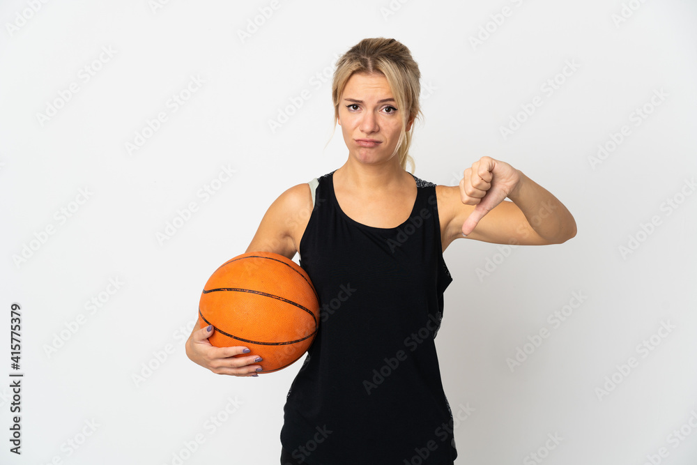 Young Russian woman playing basketball isolated on white background showing thumb down with negative expression
