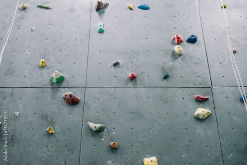 Close up photo of a rock climbing wall with climbing holds in gym photo