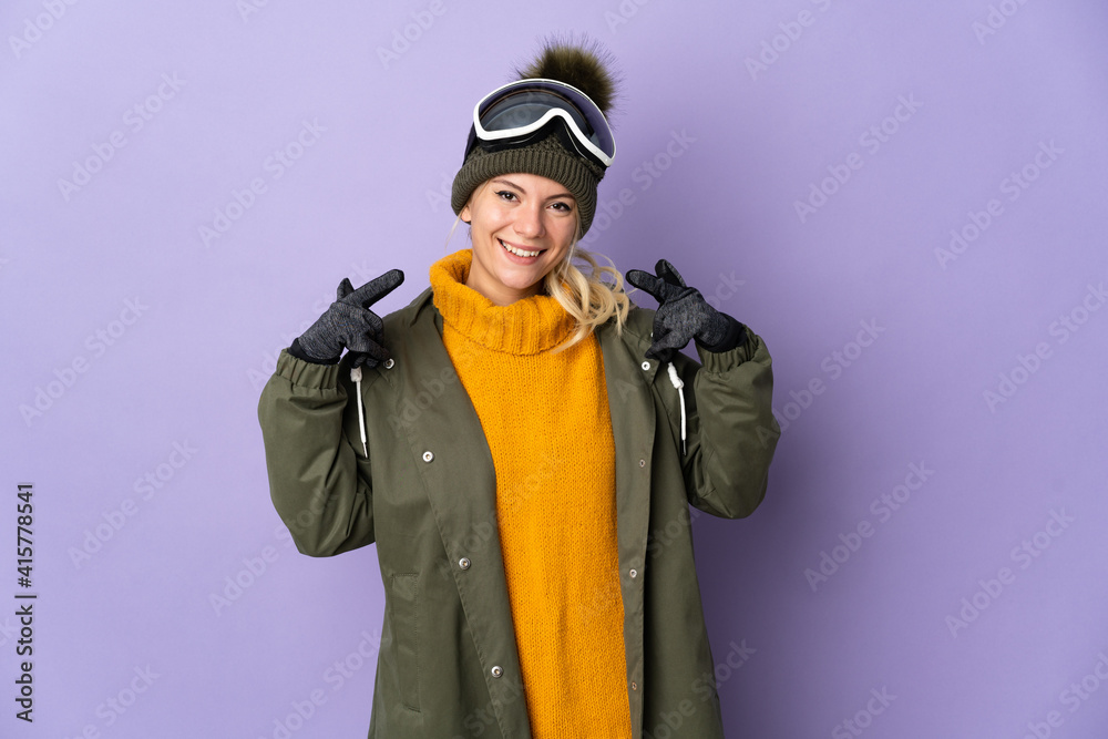 Skier Russian girl with snowboarding glasses isolated on purple background giving a thumbs up gesture Skier Russian girl with snowboarding glasses isolated on purple background giving a thumbs up gesture