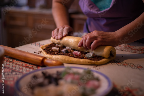 housewife rolling the dough filled with sweet ingredients to be placed in the oven tray. a traditional homemade cake recipe known as cozonac