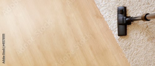Obraz na plátne Modern vacuum cleaner on a beige carpet on a background wooden light coloured parquet