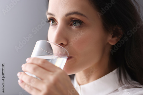 Bilde på lerret Young brunette woman drinking water from glass
