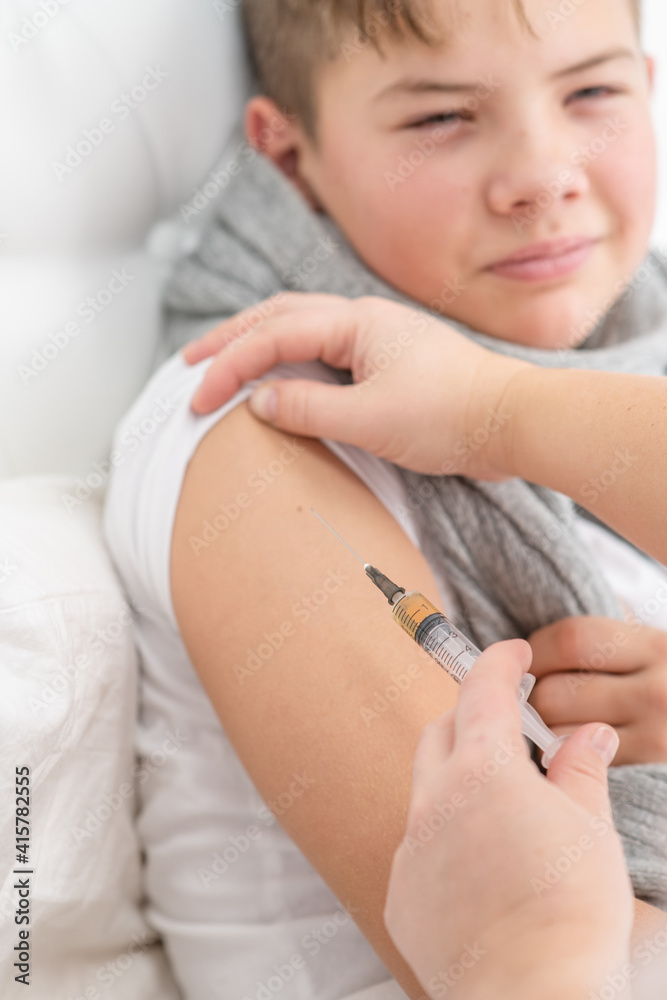 A boy is given a shot in the shoulder at the hospital. Vaccinating children