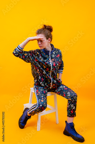 Stylish young girl posing on stepladder over orange background