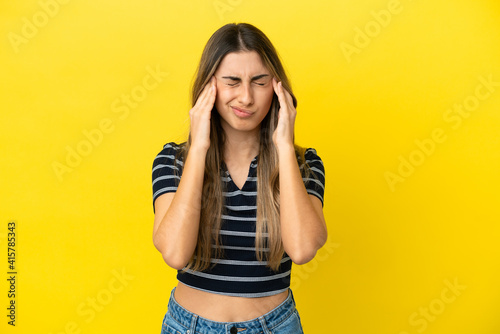 Young caucasian woman isolated on yellow background with headache