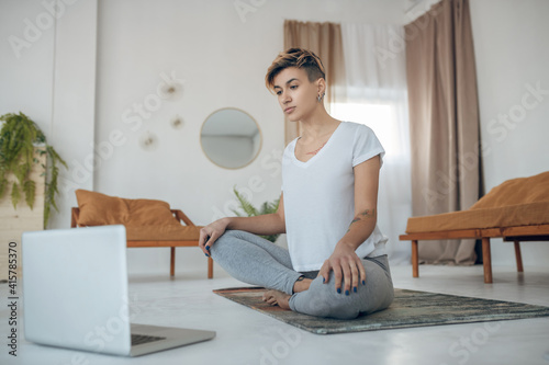 Short-haired young girl doing yoga at home and looking involved