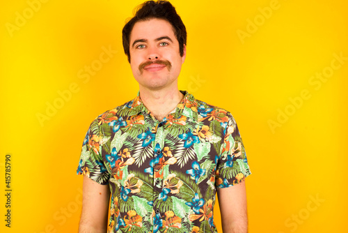 Wallpaper Mural Happy young handsome Caucasian man wearing Hawaiian shirt against yellow wall looking at camera with charming cute smile. Torontodigital.ca