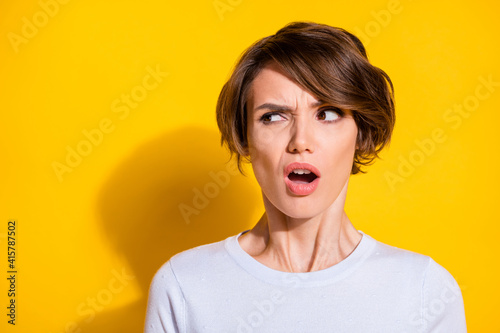 Photo of adorable shocked young woman wear white shirt looking empty space isolated yellow color background