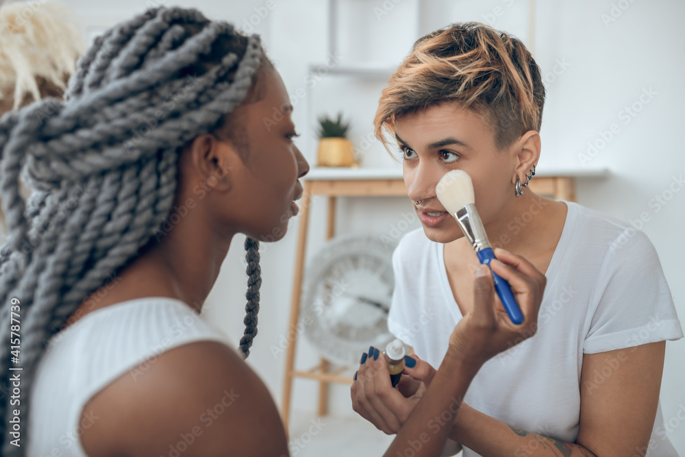African american girl doing make up to her girlfriend African american girl doing make up to her girlfriend