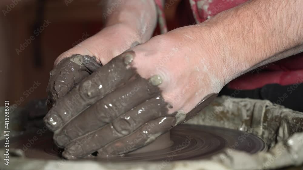 A potter's hands are beginning to shape a vase that spins on the potter's wheel with the force of his thumbs FDV A potter's hands are beginning to shape a vase that spins on the potter's wheel with the force of his thumbs FDV