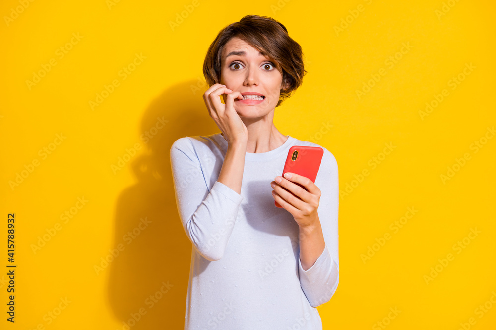 Photo of adorable frightened young woman wear white shirt writing modern device isolated yellow color background Photo of adorable frightened young woman wear white shirt writing modern device isolated yellow color background