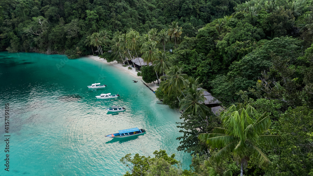 Boats Near Ocean Beach With Huts Among Palm Trees In Kaimana Island, Raja Ampat. Stunning View From Drone On Water Transport In Turquoise Lagoon Near Tropical Resort In Papua, Indonesia.