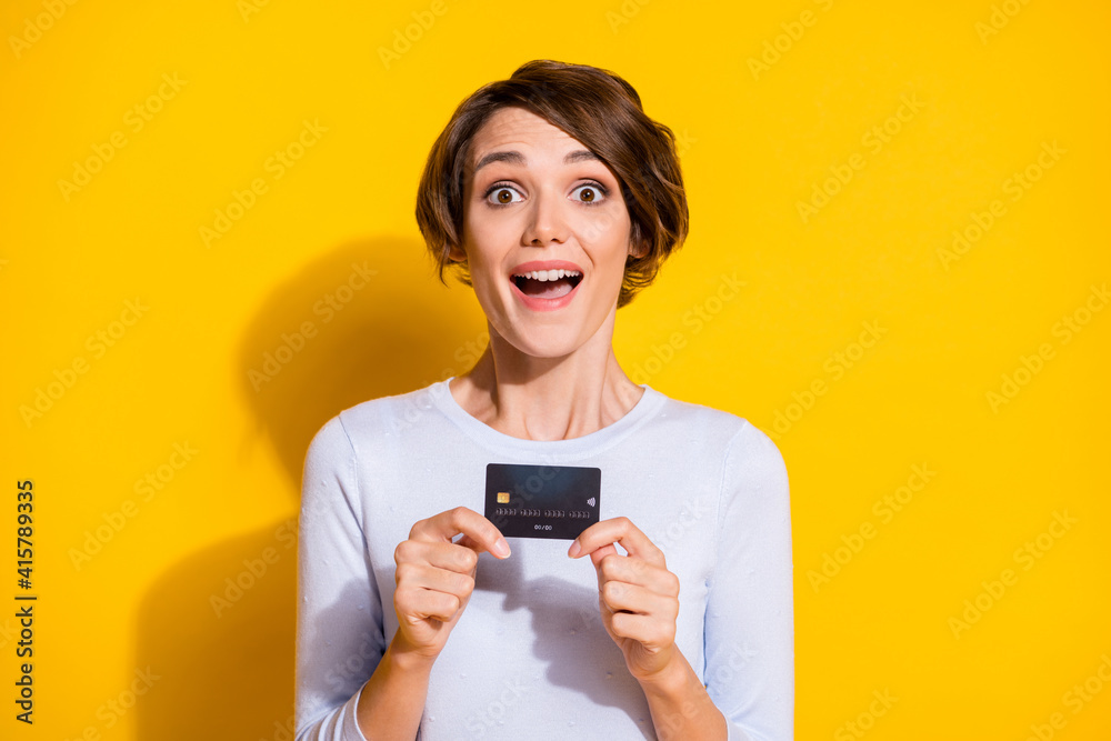 Photo of pretty charming young lady dressed white shirt holding bank credit card isolated yellow color background Photo of pretty charming young lady dressed white shirt holding bank credit card isolated yellow color background
