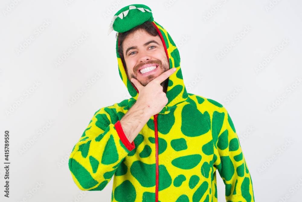 Fototapeta premium young caucasian man wearing a pajama standing against white wall looking confident at the camera smiling with crossed arms and hand raised on chin. Thinking positive.