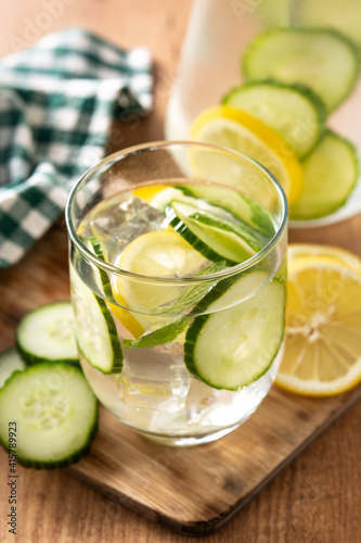 Sassy water or water with cucumber and lemon on wooden table