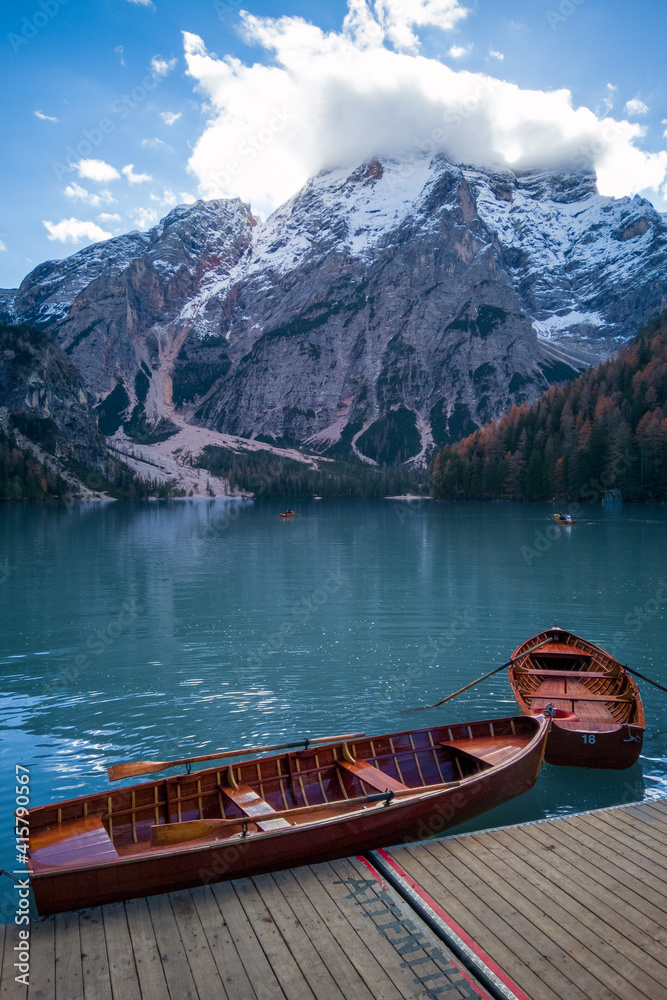 Pair of wooden rowing boats at wooden pier on Lake Braies with mount Croda del Becco top hidden in clouds. Nature in northern Italy.