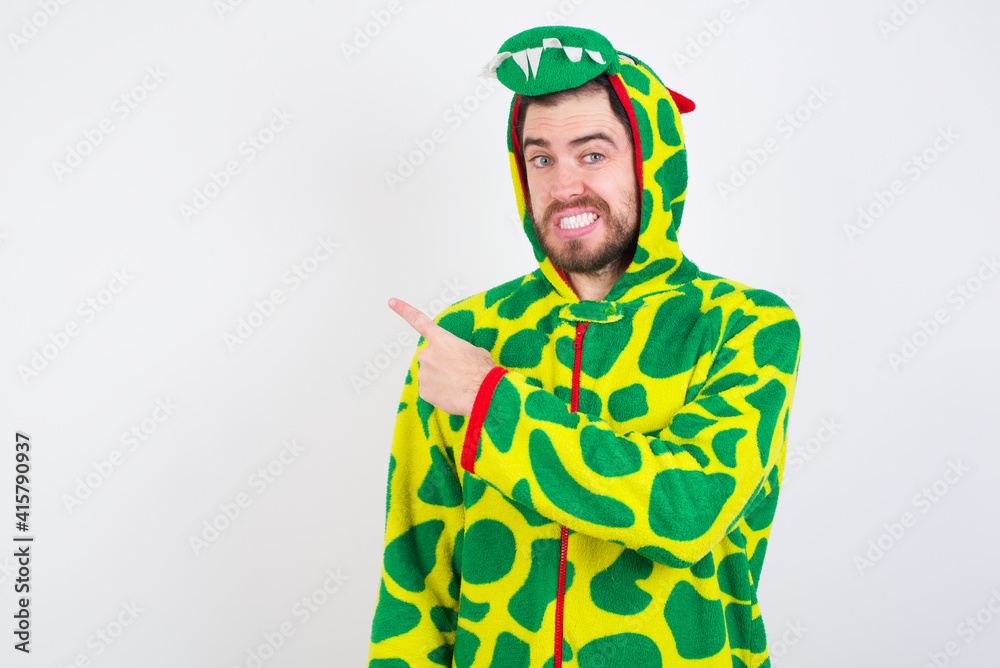Fototapeta premium young caucasian man wearing a pajama standing against white wall Pointing aside worried and nervous with forefinger, concern and surprise concept.
