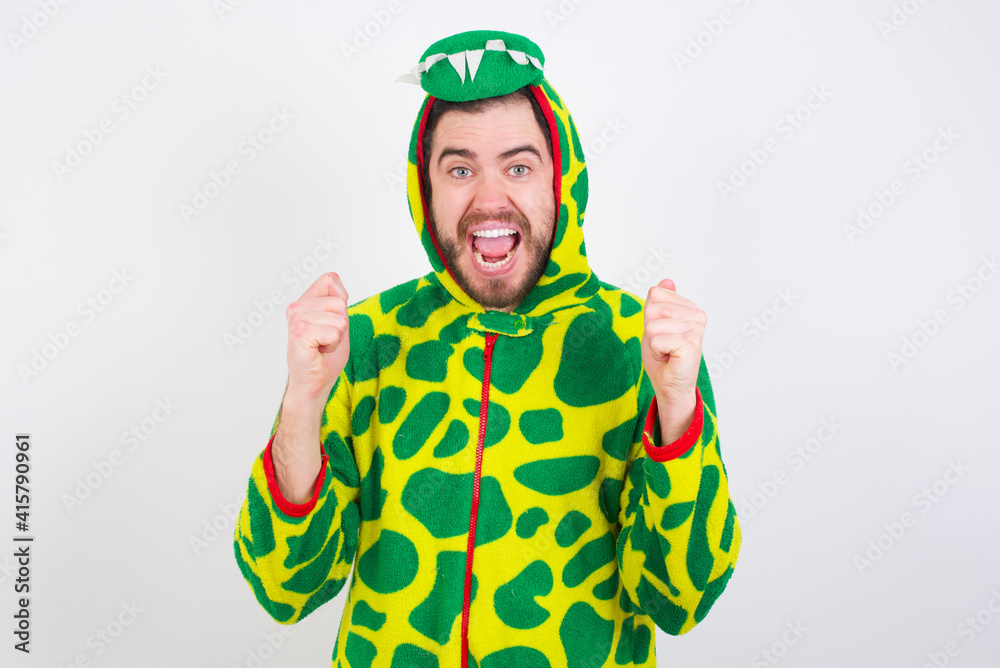 Fototapeta premium young caucasian man wearing a pajama standing against white background celebrating surprised and amazed for success with arms raised and open eyes. Winner concept.