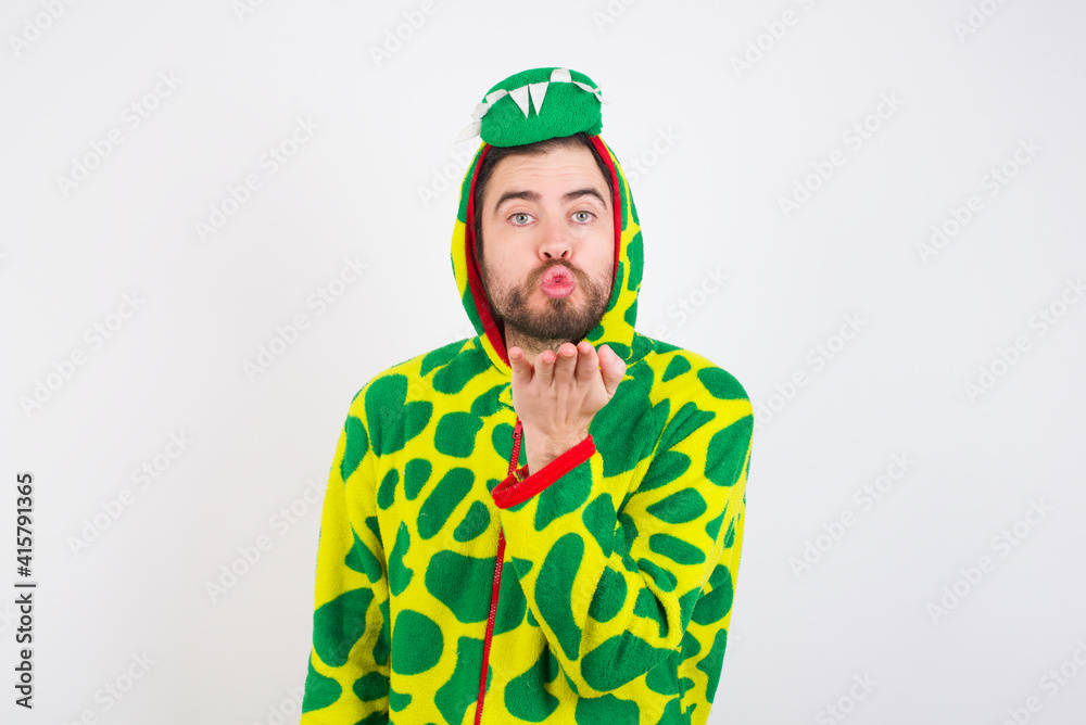 Fototapeta premium young caucasian man wearing a pajama standing against white background looking at the camera blowing a kiss with hand on air being lovely and sexy. Love expression.