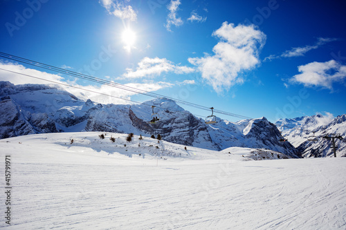 Ski lift over mountain peaks panorama with clean fresh trails in Pralognan-la-Vanoise range and snowy tops in French Alps
