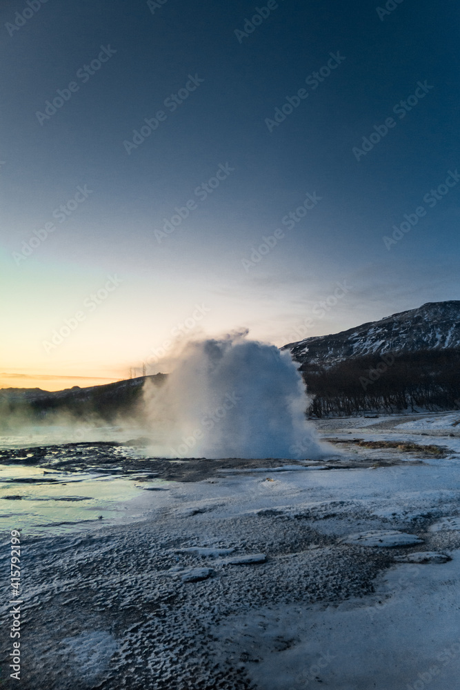 View on geothermal hot natural spring. Steam emitted from geyser at sunset time. Preserved nature in Iceland. Winter landscape.