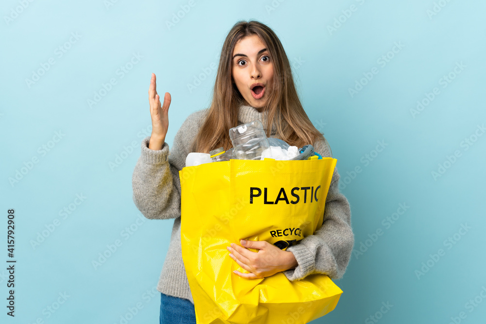 holding a bag full of plastic bottles to recycle over isolated blue with surprise facial expression holding a bag full of plastic bottles to recycle over isolated blue with surprise facial expression