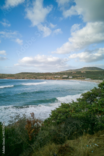 Scenic view of crashing waves at coast  Sardinia  Italy. Several people on sandy beach in wild water. Summer vacation concept.