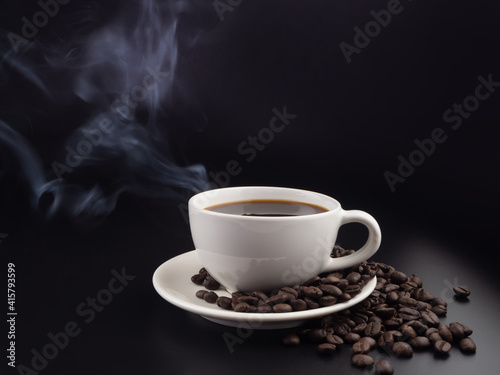 A cup of hot black coffee on black background with hot steam